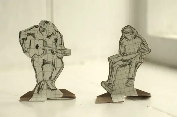 Beresford Marsh represented as two cardboard figures, sketched on paper with grid patterns, play instruments. One stands, the other sits. Soft lighting, minimalist setting.