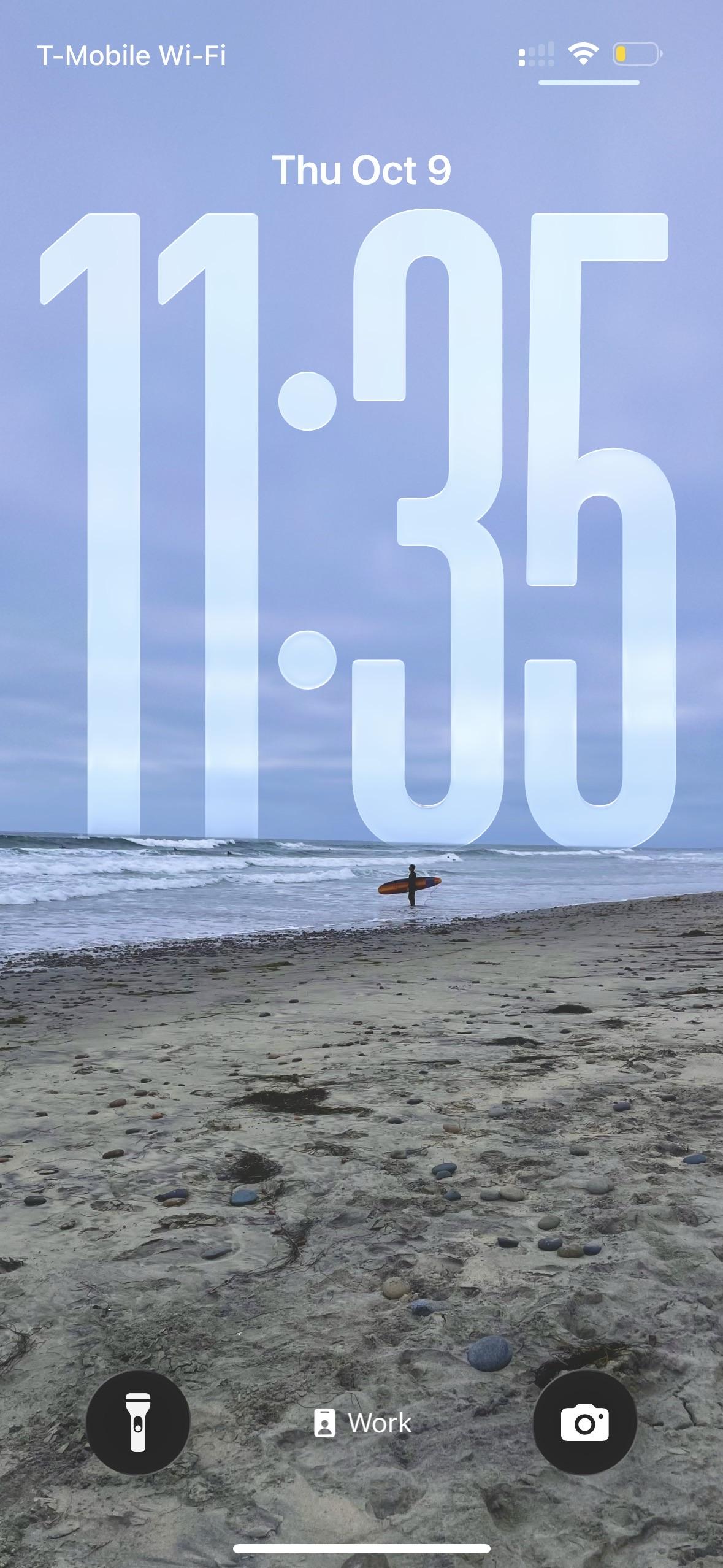 Lock screen shot: A lone surfer looks out into the ocean on the beach. The time reads 11:35. 