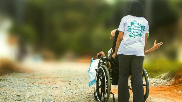 Person pushing someone in a wheel chair.
