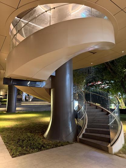 Hell und dunkel im Kontrast bei diesem Spiralstaircase. Weisse aussenverkleidung, schwarze stufen und Mittelsäule. Alles im warmen Abendlicht mit grünen gras- und Baumakzenten drumrum