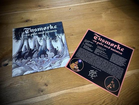 Ein Albumcover mit dem Titel "Tusmørke - en pakt med naturen" mit einer gemalten Waldszene, die Figuren und Tiere zeigt. Daneben befindet sich die Innenhülle mit einem dunklen Hintergrund, auf dem Texte und Bilder zum Album zu sehen sind.