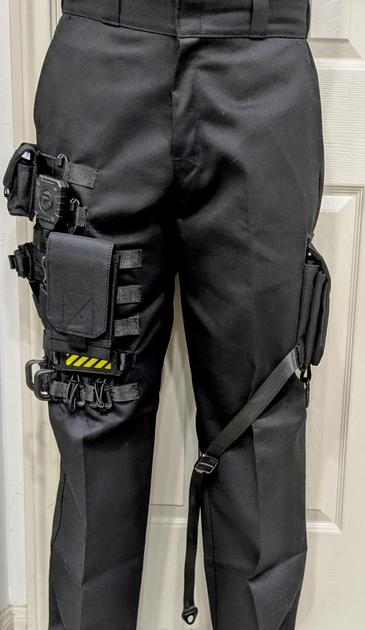 Black pants with MOLLE webbing on one leg and a collapsed cargo pocket on the other.