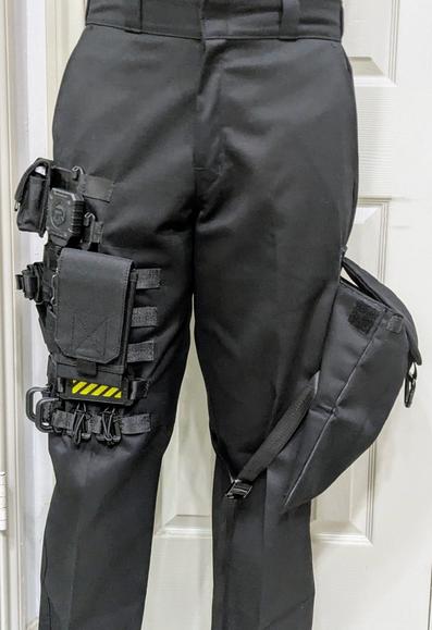 Black pants with MOLLE webbing on one leg and an expanded cargo pocket on the other 