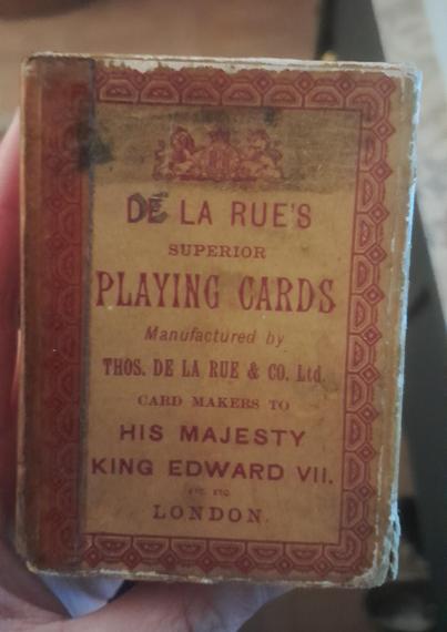 The front of the card deck pack.

"DE LA RUES
SUPERIOR
PLAYING CARDS
MANUFACTURED BY
THOS. DE LA RUE & CO. Ltd
CARD MAKERS TO
HIS MAJESTY 
KING EDWARD VII
ETC ETC
LONDON"
