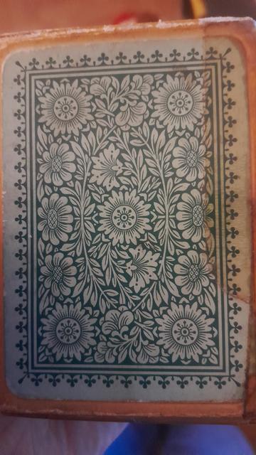 Back of the card deck pack. 

I green floral leaf like pattern which I thought was suppose to depict the card back but ain't. 

Is this an old box and the cards inside are wrong idk. They all look the same age.