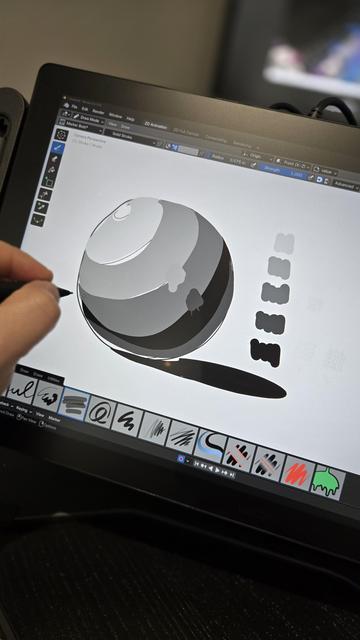 Close up of cintiq with blender interface, a sphere sketched on display, some Grey swatches to the right. Left hand wearing smudge guard holding Pro pen 3 hovers above it