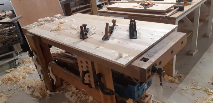 Mon établi, autre angle se vue, avec le plateau de table dessus, lui-même avec des rabots dessus : n°5, n°4 et un 5 a angle faible (n°61 je sais plus).

On voit des copeaux partout. 
On est sur la fin, la table brille.