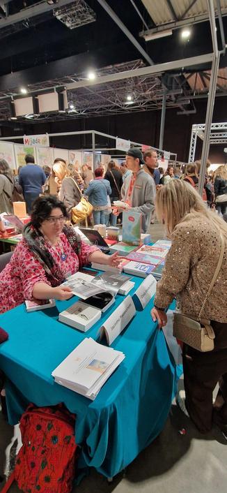 Photos prises sur le stand de l'adeb au salon éduc. Sur la photo Cindy Vandermeulen présente livre légitimes de nafi yao paru chez courgette Éditions à une enseignante.