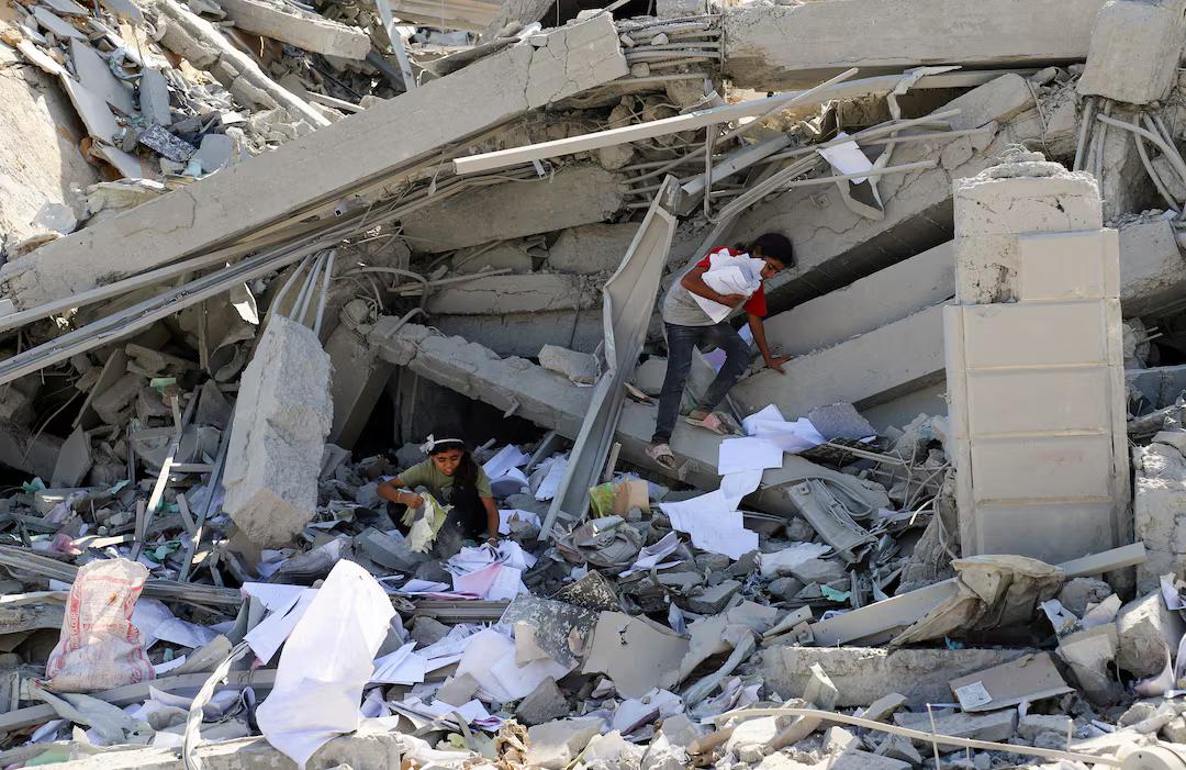 Children collect paper amongst the rubble.