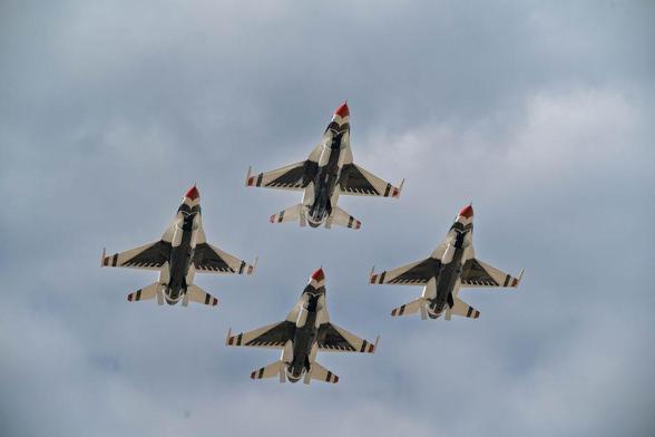 Four U.S. Air Force Thunderbirds F-16 jets fly in a tight diamond formation against a cloudy sky, viewed from directly below. The image captures the symmetry and precision of the flight team, photographed with a Nikon Zf and Sigma 150–600mm lens.