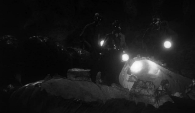 an image of men in a dark cave with flashlights, facing the viewer