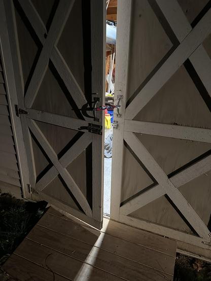 Photo of the outside of the shed with light creeping out of the cat-sized crack I left open, secured with a bungee cord.
