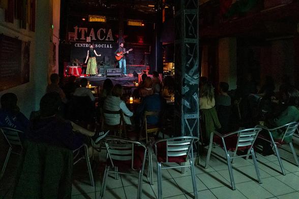 Yaima Orozco y Migue de la Rosa en el escenario del CS Ítaca. Vista desde atrás de la sala central, con el público alrededor del escenario.
