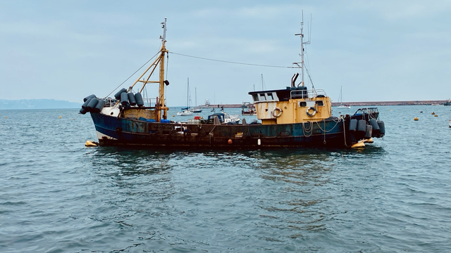 A beaten up and well used fishing boat moored up on an outer mooring in Brixham Harbour