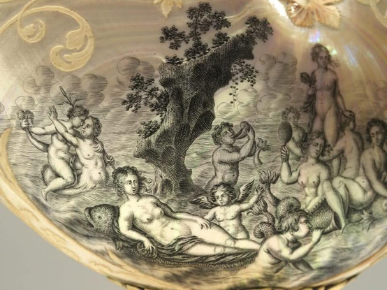 Das Bild zeigt eine mit einem Fuß versehene Schale. Die Schale selbst ist in Form einer Nautilus-Muschel gefertigt und hell und uneben gefärbt. Die Innenseite der Schale ist mit einer Reihe von kleinen Figuren in Schwarz und Weiß verziert. Der Fuß der Schale ist aus Gold gefertigt und verziert mit geometrischen Mustern. Die Schale steht auf einer hellen Oberfläche.
Bereitgestellt von @altbot, privat und lokal generiert mit Gemma3:27b