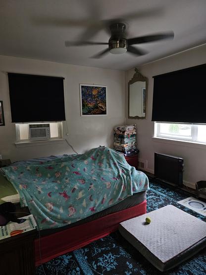 A bed covered in blankets. Just over the top of the foot of the bed you can see two cat ears.