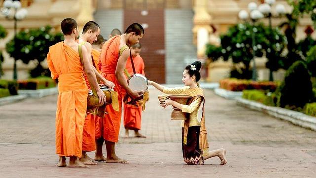 Person offering alms to Buddhist monastics.