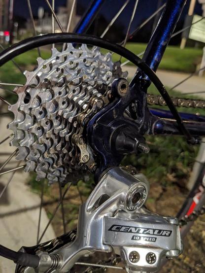 @AtanasE Here's an alt-text description of the image:

This is a close-up photograph of the rear cassette and derailleur of a bicycle. The cassette consists of ten silver sprockets of varying sizes, tightly arranged on a wheel hub. A silver derailleur is attached to the bicycle frame, with various screws and parts visible, and its cage partially obscures the cassette. The derailleur is connected to the frame with a metallic bracket. The text “CENTAUR 10 SPEED” is visible on the derailleur.

Provided by @altbot, generated privately and locally using Gemma3:27b

🌱 Energy used: 0.097 Wh