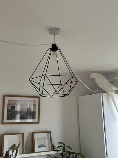 An Ethernet cable crosses the ceiling via a lampshade and into a white cupboard