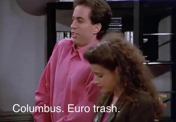A scene from a sitcom Seinfeld featuring two characters, Jerry, wearing a pink shirt and Elaine wearing a dark blazer. Jerry is speaking with a smirk, while the Elaine looks down. Text on the image reads, "Columbus. Euro Trash"