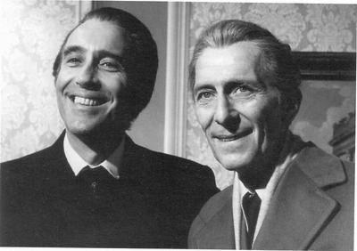 A black-and-white photograph of best friends and British actors Christopher Lee and Peter Cushing on the set of the 1973, British, Hammer Horror film “The Satanic Rites of Dracula”. They are both smiling at the camera while wearing suits and ties.
