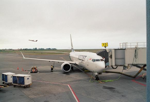 An airliner on the ground at the gate. You can see one of the deck crew leaning out of the port side of the cockpit. Possibly cleaning the windshield. 

A prop job takes off in the background. 

Kodak Portra 800
AF Nikkor 35mm f2.0 D 
Nikon FA 