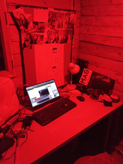 computer on messy desk lit by red light