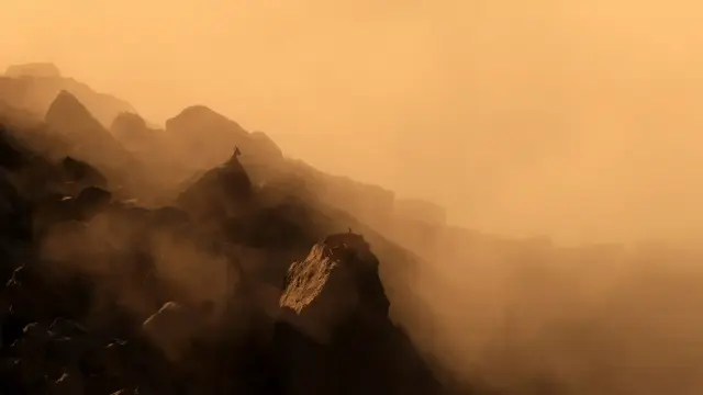 Mist-shrouded mountains with a silhouetted Alpine ibex in sepia tones.
