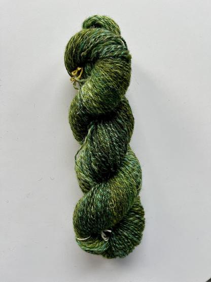 Twisted up hank of fine green yarn in many different tones.