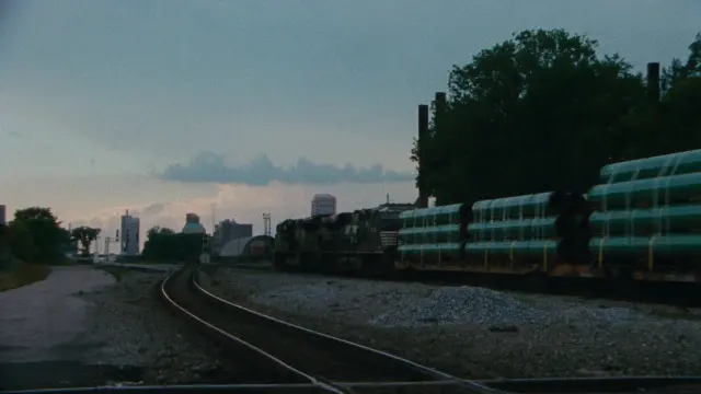 still of the documentary film "The Magic City - Birmingham According to Sun Ra" by Guillaume Maupin & Pablo Guarise - railroad tracks, freight train and skyline of buildings in Birmingham