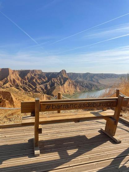 Banco de madera en primer plano con las cárcavas de Burujón de fondo