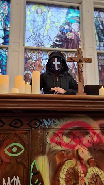 Pictures from immersive art exhibition hooded figure with white cross mask in front of altar with crucifix, candles on it and stained glass behind it, graffiti on altar