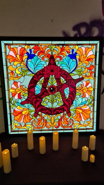 Stained glass window with red anarchy symbol with eye in middle