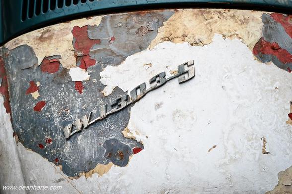 Close-up of the rear of a 1970s Volkswagen Beetle 1300 showing the chrome badge on a weathered, peeling surface of rust and paint layers in Bangkok. The 1303 S badge does not actually belong on this car and was taken from a different model!