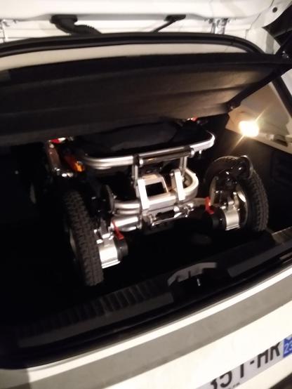 Photo du même fauteuil plié dans un coffre de clio dont il occupe les trois quarts de la largeur