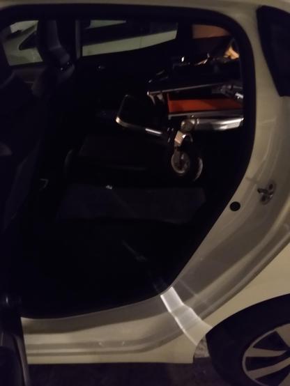 Photo du même fauteuil plié dans un coffre de Clio vu par la portière passager. Il avance jusqu'au tiers du siège passager