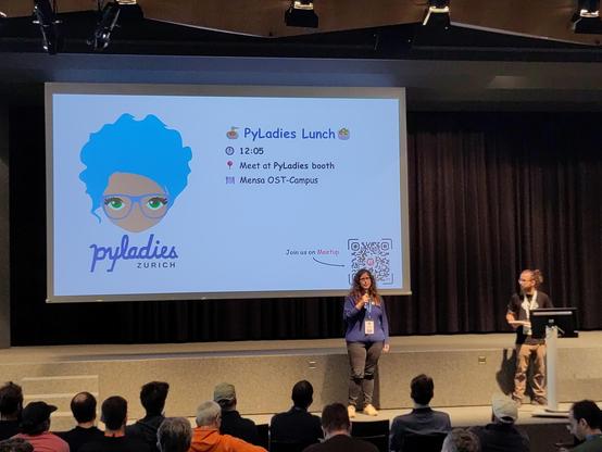 a pylady announcing the pyladies lunch in front of a huge slide with a pyladies logo