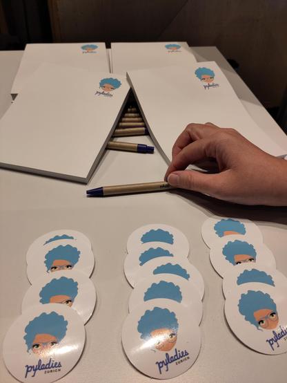 pyladies stickers, pens and notepads on a table