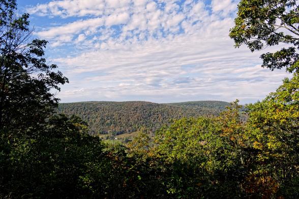 Very early fall color,  still dominantly green foilage in the near field and also on distant hills under a blue and white sky