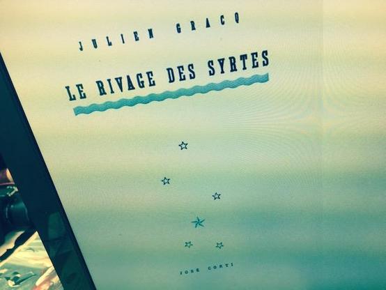 Un jeune aristocrate d’Orsenna, Aldo, est nommé « observateur » sur le rivage des Syrtes, frontière maritime face au lointain Farghestan, ennemi officiel mais endormi depuis trois siècles. Il découvre un État décadent qui a fait de l’attente sa politique : flottes désarmées, fortins en ruine, traités tabous. Aimanté par la mer interdite et par une grande dame de la cité, il franchit peu à peu les limites : patrouilles plus loin que la ligne fixée, exploration d’îles et de passes, interrogation des archives et des secrets d’État. Cette curiosité devient transgression ; un geste symbolique relance le jeu stratégique et provoque l’engrenage. Les signaux se rallument, les ports s’animent, les escadres sortent : la « veille » bascule en guerre. Roman d’atmosphère et de seuils, Le Rivage des Syrtes décrit la fin d’un monde figé, happé par le désir d’éprouver le réel. Thèmes centraux : fascination du dehors, fatalité historique, politique de l’évitement, géographie comme destin. Style : phrases longues, cartographie précise, métaphores de brumes, d’eaux et de lisières qui rendent perceptible la carte d’un empire au moment où il se réveille.