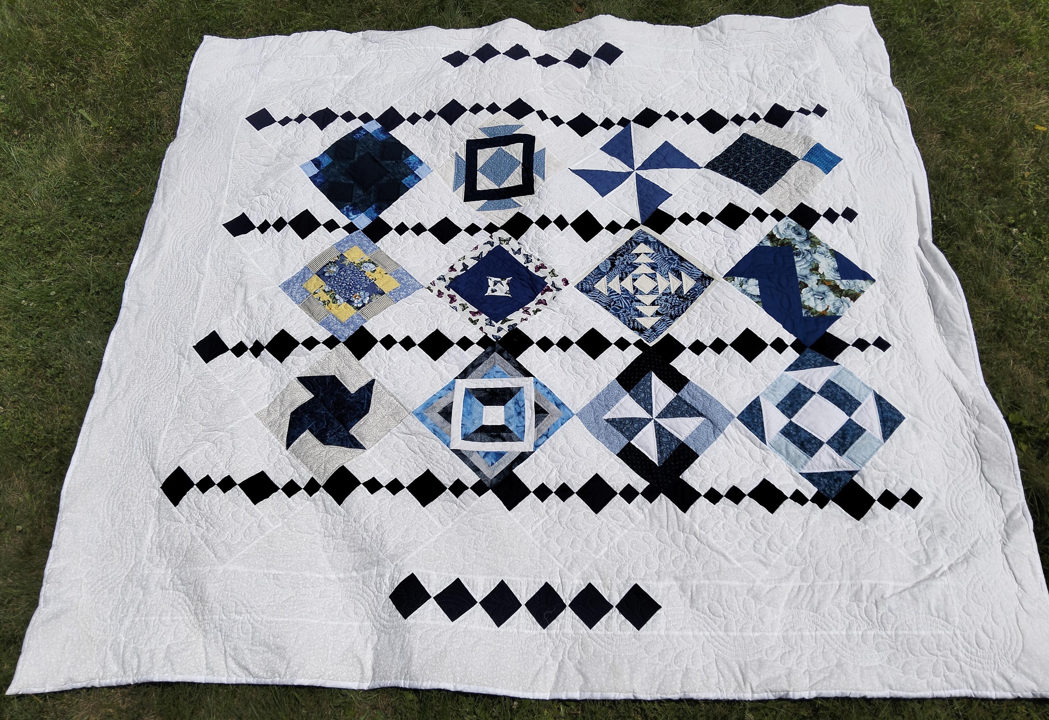 93 x 89 in (236 x 226), it is a chandelier design quilt, there are strips of unique blue and white shapes divided by strips of cascading dark blue diamond shapes