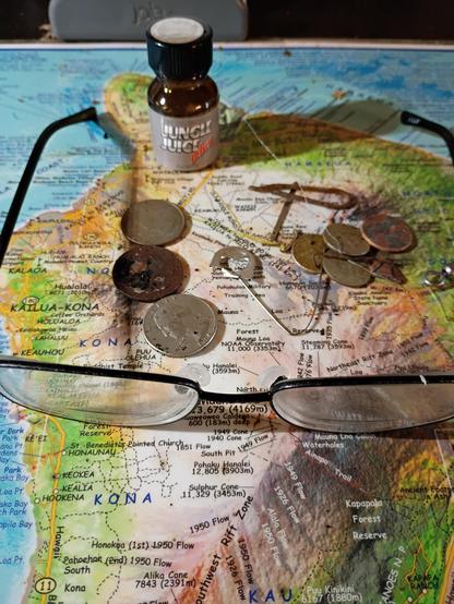 Metal detecting finds including coins, a pair of bifocals and a bottle of poppers.