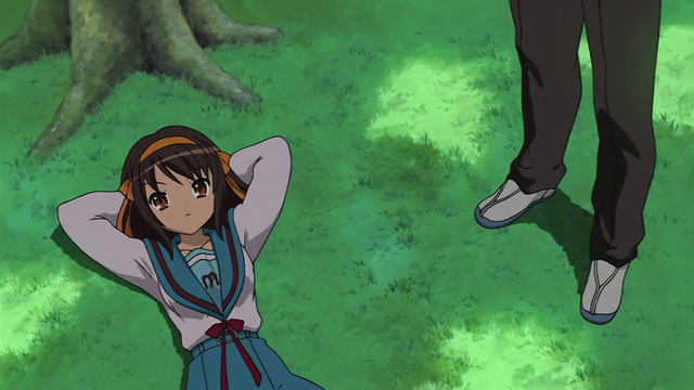 A girl (Haruhi) laying back under a tree with her arms folded behind her head while a boy (Kyon) appears to be standing in frame.
