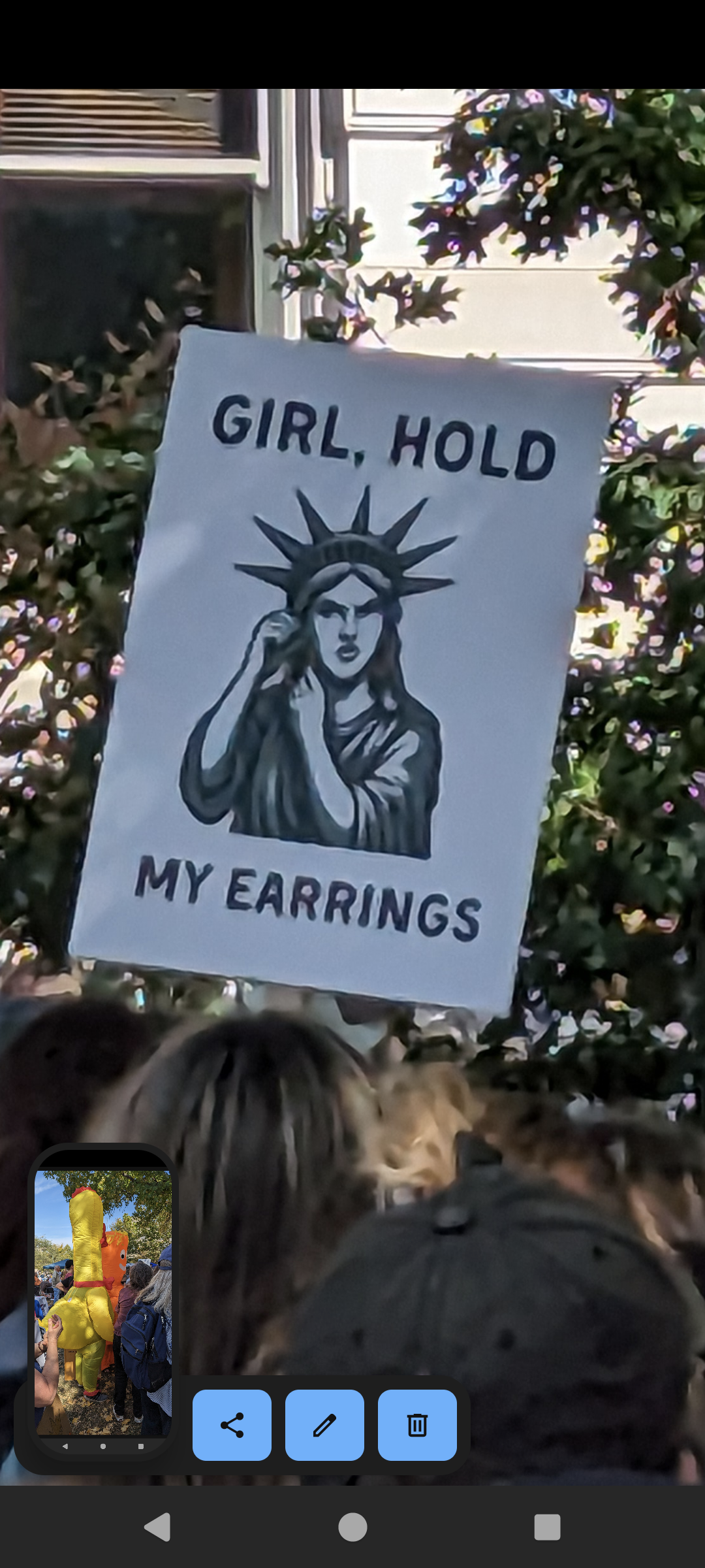 Protest sign showing statue of liberty taking off earring saying girl, hold my earrings