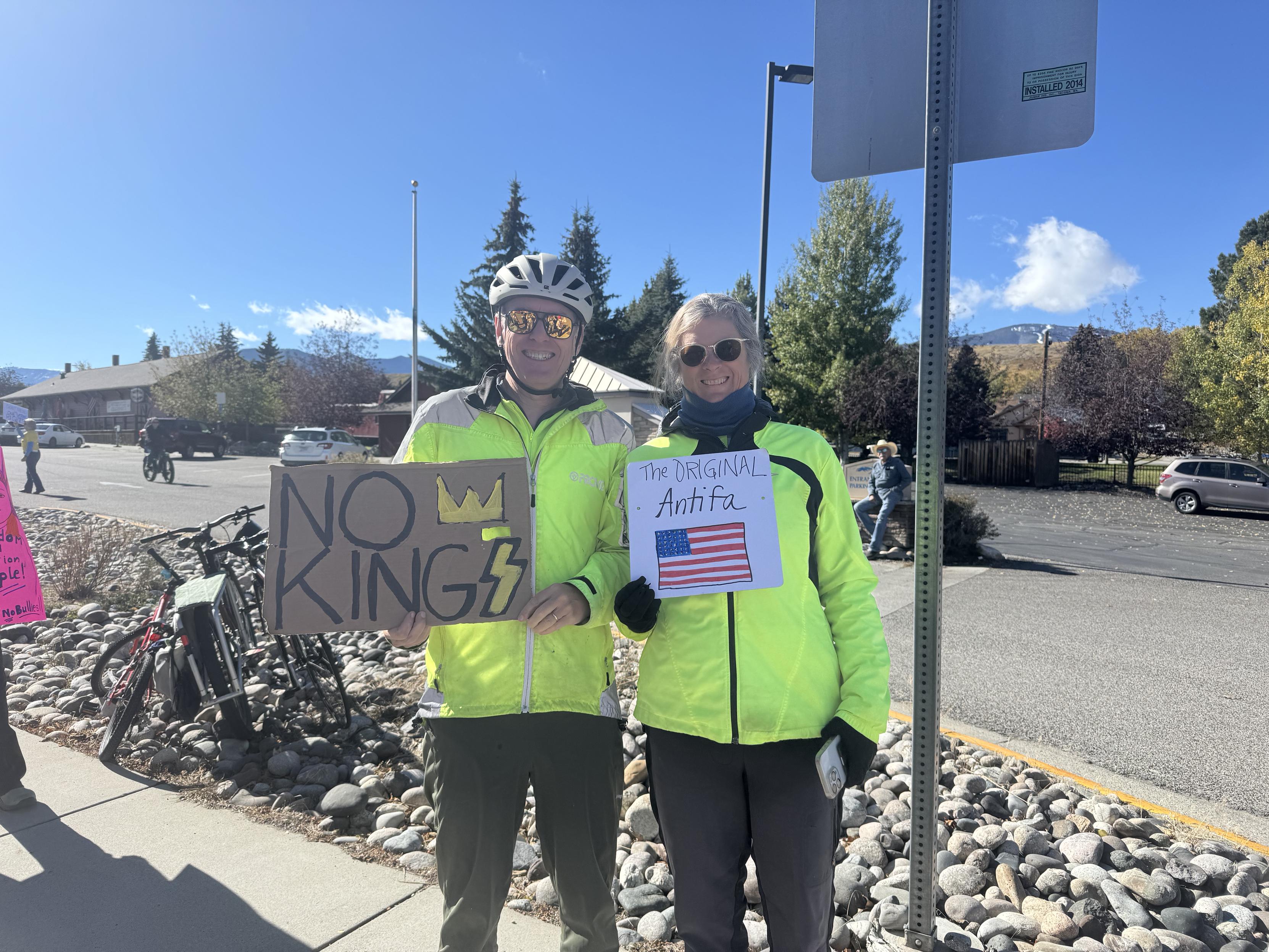 Two cyclists in hi viz yellow holding no kings signs at a protest rally in Red Lodge Montana