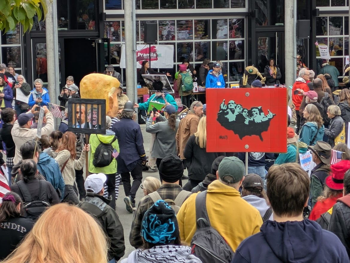 Signs at the rally included vivid takes on the gestures made by the presidents at Mount Rushmore and various versions of the current officeholders, including one in a fat suit with a crown and red cape and a sign that pointed out the emperor's lack of clothing.