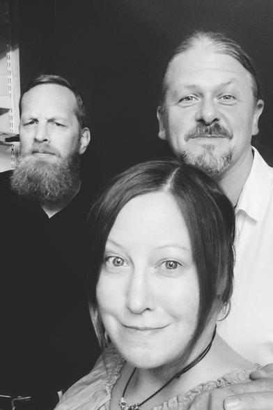 S/W-Gruppenbild als Selfie von einer Frau im Vordergrund und zwei bärtigen Männern im Hintergrund, die freundlich in die Kamera schauen. Nur der Mann links im Hintergrund schaut ernsthaft bis skeptisch. 