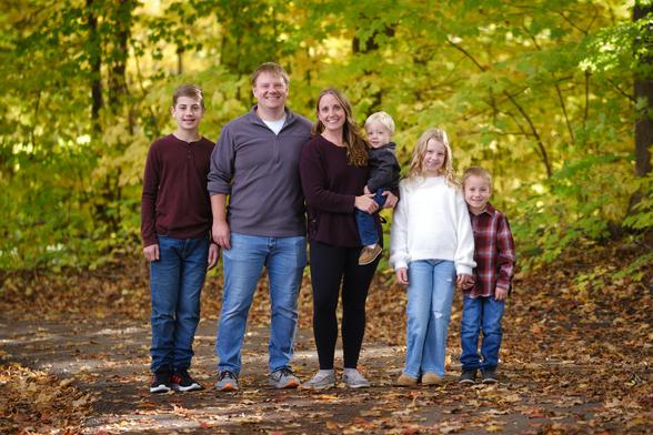 A family with four kids poses for a photo on a forest path on a nice autumn day