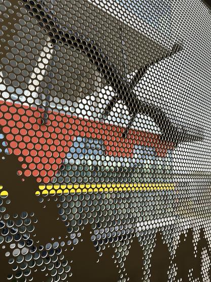 Building with several high floors, with external staircases. Seen through a grid, depicting waiting people.