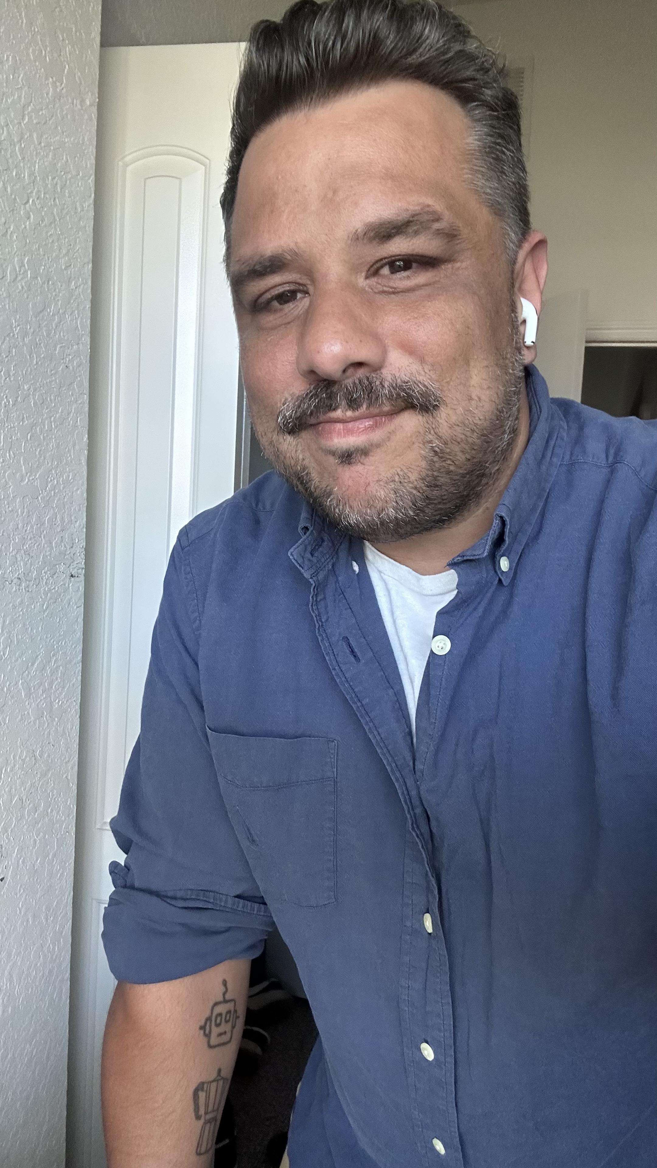 Me in a navy blue collar shirt with a white under shirt. I'm wearing earbuds